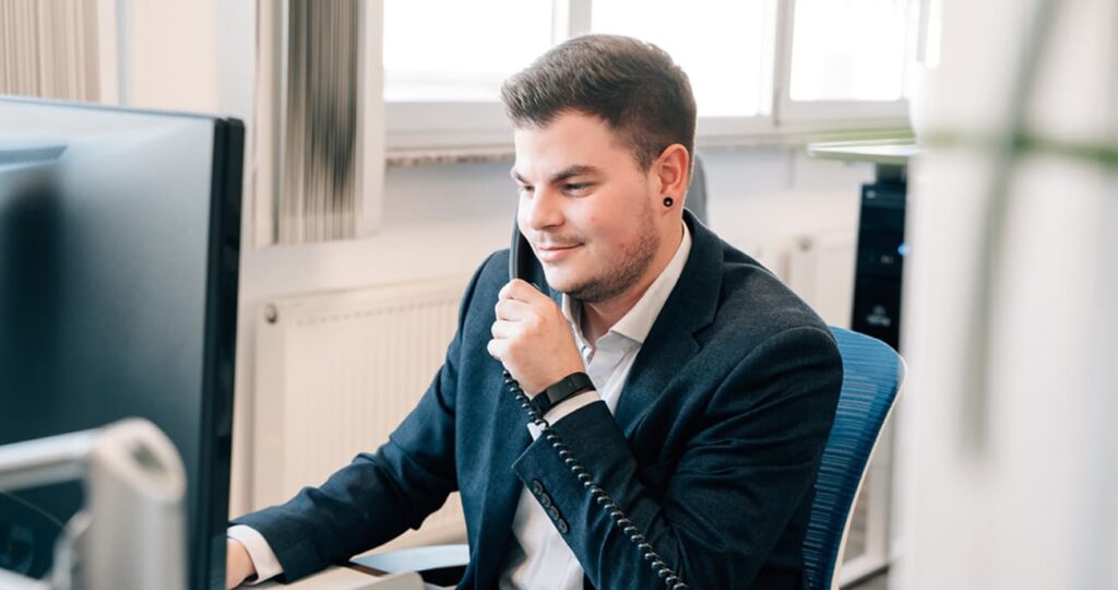 Ein Servicemitarbeiter sitzt an seinem Arbeitsplatz und führt gerade ein Telefonat